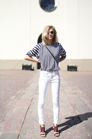 dunkelblaues und weißes horizontal gestreiftes Langarmshirt, weiße enge Jeans, dunkelrote Leder Sandaletten, graue Sonnenbrille für Damen