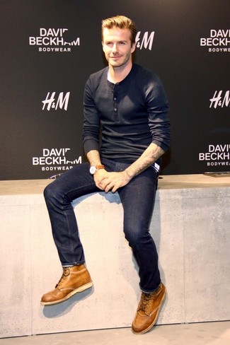 David Beckham trägt schwarzes Langarmshirt mit einer Knopfleiste, dunkelblaue Jeans, beige Lederfreizeitstiefel, braune Lederuhr