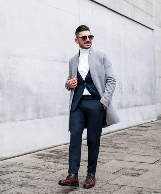 Dunkelrote Brogue Stiefel aus Leder kombinieren – 23 Herren Outfits: Kombinieren Sie einen grauen Mantel mit einem dunkelblauen Anzug für eine klassischen und verfeinerte Silhouette. Dunkelrote Brogue Stiefel aus Leder verleihen einem klassischen Look eine neue Dimension.