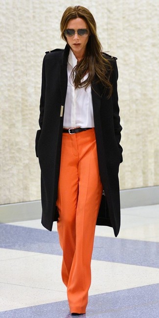 Victoria Beckham trägt schwarzer Mantel, weißes Businesshemd, orange weite Hose, schwarzer Ledergürtel