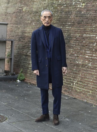 60 Jährige: Outfits Herren 2024: Kombinieren Sie einen dunkelblauen Mantel mit einem dunkelblauen Anzug, um vor Klasse und Perfektion zu strotzen. Dunkelbraune Chukka-Stiefel aus Wildleder verleihen einem klassischen Look eine neue Dimension.