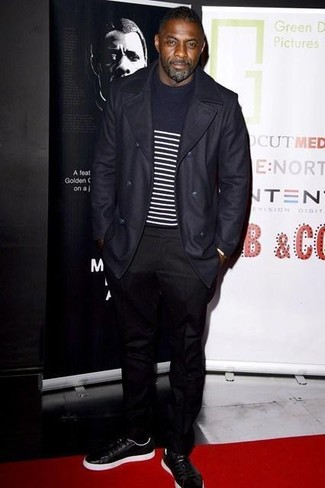 Idris Elba trägt dunkelblauer Mantel, dunkelblauer und weißer horizontal gestreifter Pullover mit einem Rundhalsausschnitt, schwarze Chinohose, schwarze Leder niedrige Sneakers