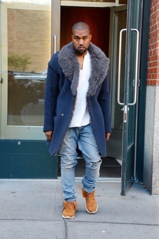 Kanye West trägt blauer Mantel mit einem Pelzkragen, weißes T-shirt mit einer Knopfleiste, hellblaue Jeans mit Destroyed-Effekten, rotbraune Chukka-Stiefel aus Wildleder