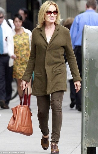 Jessica Lange trägt olivgrüner Mantel, olivgrüne Jeans, braune Leder Oxford Schuhe, beige Shopper Tasche aus Leder