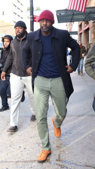 Idris Elba trägt dunkelblauer Mantel, dunkelblauer Pullover mit einem Rundhalsausschnitt, mintgrüne Chinohose, rotbraune niedrige Sneakers