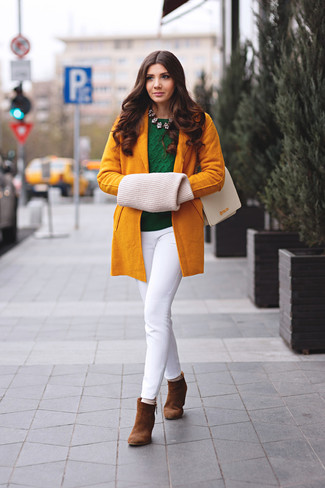 senf Mantel, dunkelgrüner Pullover mit einem Rundhalsausschnitt, weiße enge Hose, braune Wildleder Stiefeletten für Damen