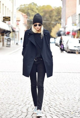 schwarzer Mantel, schwarzer Pullover mit einem Rundhalsausschnitt, schwarze enge Jeans, hellblaue niedrige Sneakers für Damen