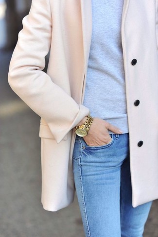 rosa Mantel, grauer Pullover mit einem Rundhalsausschnitt, hellblaue enge Jeans, goldene Uhr für Damen