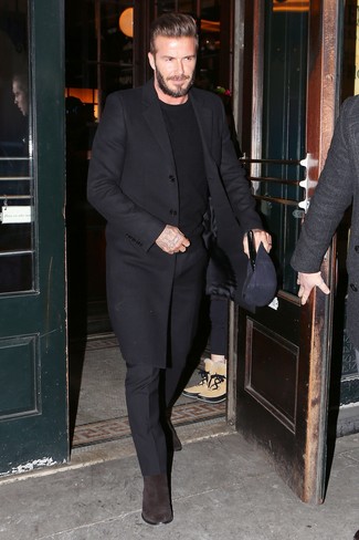 David Beckham trägt schwarzer Mantel, schwarzer Pullover mit einem Rundhalsausschnitt, schwarze Anzughose, dunkelbraune Chelsea-Stiefel aus Wildleder