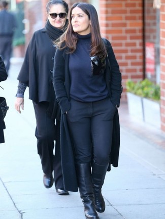 Salma Hayek trägt schwarzer Mantel, dunkelblauer Rollkragenpullover, schwarze enge Hose, schwarze kniehohe Stiefel aus Leder