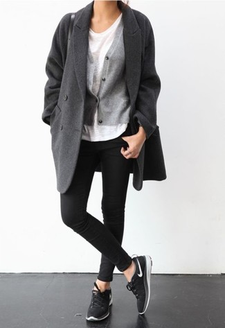 dunkelgrauer Mantel, graue Strickjacke, weißes T-Shirt mit einem Rundhalsausschnitt, schwarze enge Jeans für Damen