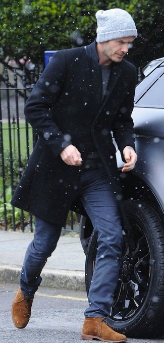 David Beckham trägt schwarzer Mantel, dunkelgraues T-Shirt mit einem Rundhalsausschnitt, dunkelblaue Chinohose, rotbraune Chukka-Stiefel aus Wildleder
