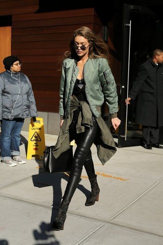 Gigi Hadid trägt olivgrüne Militärjacke, olivgrüne Bomberjacke, schwarzes ärmelloses Oberteil, schwarze Leder enge Jeans