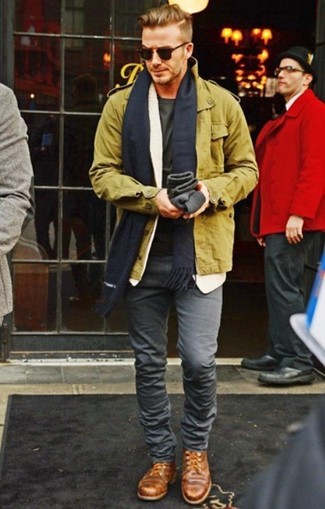 David Beckham trägt olivgrüne Militärjacke, olivgrünes T-Shirt mit einem Rundhalsausschnitt, graue enge Jeans, braune Leder Derby Schuhe
