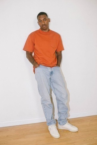 Sommer Outfits Herren 2024: Vereinigen Sie ein orange T-Shirt mit einem Rundhalsausschnitt mit hellblauen Jeans für einen bequemen Alltags-Look. Weiße Segeltuch niedrige Sneakers fügen sich nahtlos in einer Vielzahl von Outfits ein. Dieses Outfit ist hervorragend für den Sommer geeignet.