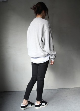Wie schwarze enge Jeans mit grauen Oversize Pullovers zu kombinieren – 33 Damen Outfits: Ein grauer Oversize Pullover und schwarze enge Jeans sind absolut Freizeit-Basics und können mit einer Vielzahl von Stücken kombiniert werden. Schwarze niedrige Sneakers sind eine großartige Wahl, um dieses Outfit zu vervollständigen.