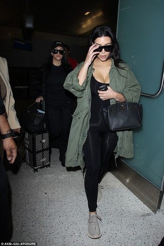 Kim Kardashian trägt olivgrüner Parka mit einem Schwalbenschwanz, schwarzer Jumpsuit, graue Sportschuhe, schwarze Satchel-Tasche aus Leder