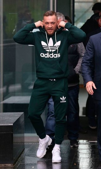 Conor McGregor trägt dunkelgrüner bedruckter Pullover mit einem Kapuze, dunkelgrüne Jogginghose, weiße Sportschuhe, weiße Socke