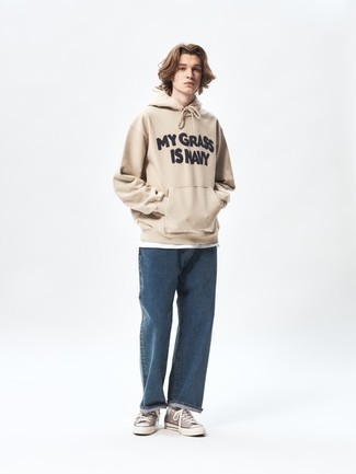 Teenager: Outfits Herren 2024: Halten Sie Ihr Outfit locker mit einem hellbeige bedruckten Pullover mit einem Kapuze und dunkelblauen Jeans.