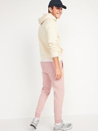 Rosa Jogginghose kombinieren – 10 Herren Outfits: Für ein bequemes Couch-Outfit, vereinigen Sie einen hellbeige Pullover mit einem Kapuze mit einer rosa Jogginghose. Komplettieren Sie Ihr Outfit mit grauen Sportschuhen.