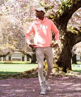 rosa Pullover mit einem Kapuze, hellbeige enge Jeans, graue hohe Sneakers aus Segeltuch, weiße bedruckte Baseballkappe für Herren