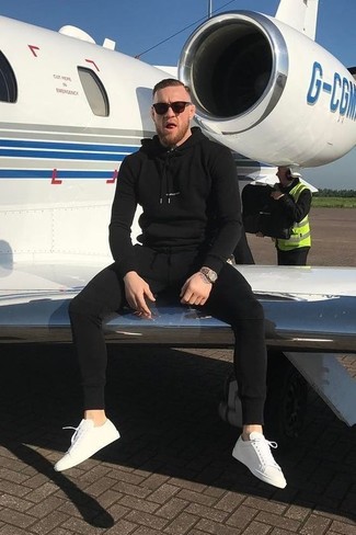 Conor McGregor trägt schwarzer Pullover mit einem Kapuze, schwarze Jogginghose, weiße Segeltuch niedrige Sneakers, goldene Uhr