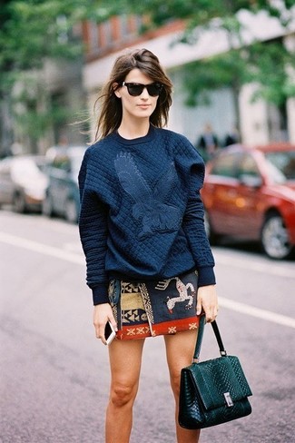 dunkelblauer gesteppter Pullover mit einem Rundhalsausschnitt, dunkelblauer bedruckter Minirock, dunkelgrüne Satchel-Tasche aus Leder, schwarze Sonnenbrille für Damen