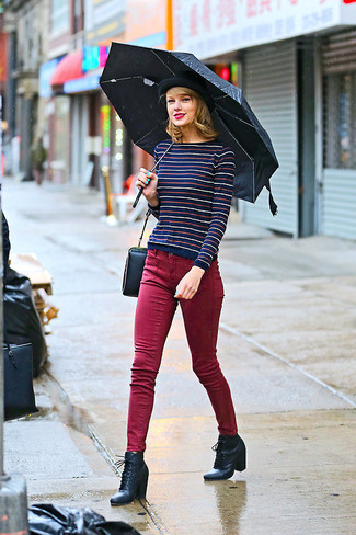 Taylor Swift trägt dunkelblauer horizontal gestreifter Pullover mit einem Rundhalsausschnitt, dunkelrote enge Jeans, schwarze Schnürstiefeletten aus Leder, schwarze Satchel-Tasche aus Leder