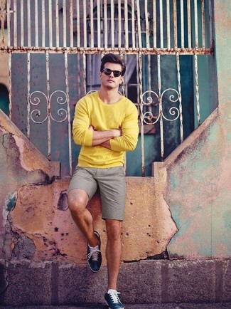 gelber Pullover mit einem Rundhalsausschnitt, graue Shorts, dunkelblaue Leder niedrige Sneakers, schwarze Sonnenbrille für Herren