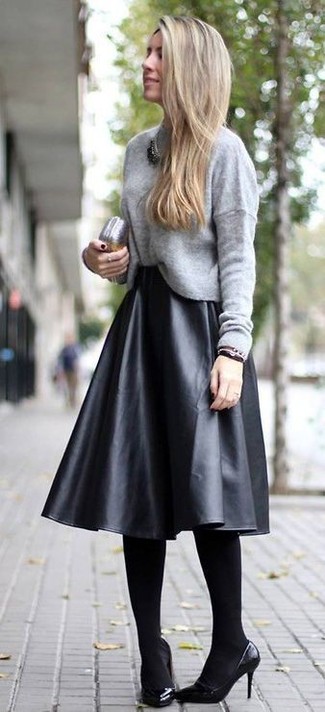 grauer Pullover mit einem Rundhalsausschnitt, schwarzer Falten Midirock aus Leder, schwarze Leder Pumps, silberne Leder Clutch für Damen