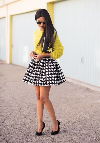 gelber flauschiger Pullover mit einem Rundhalsausschnitt, schwarzer und weißer Skaterrock mit Hahnentritt-Muster, schwarze Wildleder Pumps, schwarze bedruckte Leder Clutch für Damen