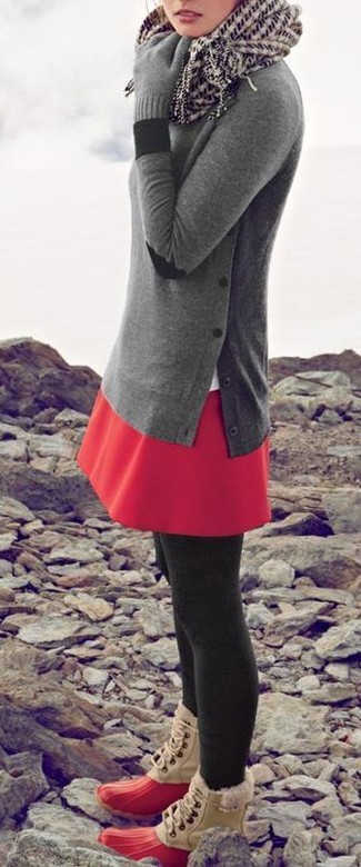 grauer Pullover mit einem Rundhalsausschnitt, roter Skaterrock, rote Winterschuhe, weißer und schwarzer bedruckter Schal für Damen
