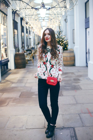 weißer Pullover mit einem Rundhalsausschnitt mit Weihnachten Muster, schwarze enge Jeans, schwarze Leder Stiefeletten, rote Leder Umhängetasche für Damen