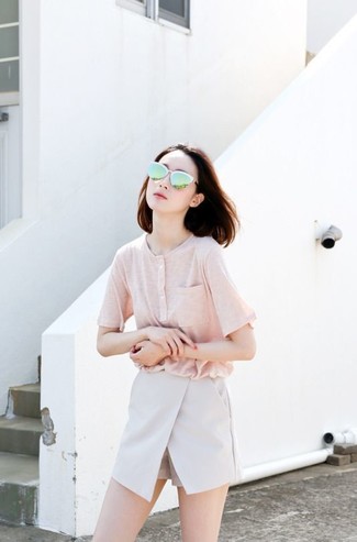 rosa T-shirt mit einer Knopfleiste, graue Shorts, grüne Sonnenbrille für Damen