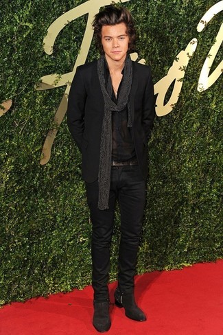 Harry Styles trägt schwarzes Sakko, schwarzes Businesshemd, schwarze enge Jeans, dunkelbraune Chelsea-Stiefel aus Wildleder