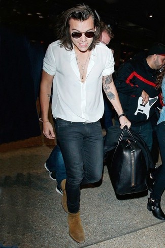 Harry Styles trägt schwarzes Sakko, weißes Kurzarmhemd, dunkelblaue enge Jeans, braune Chelsea-Stiefel aus Wildleder