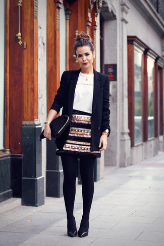 schwarzes Sakko, weißer und schwarzer bedruckter Pullover mit einem Rundhalsausschnitt, schwarzer und goldener Paillette Minirock, schwarze Leder Pumps für Damen