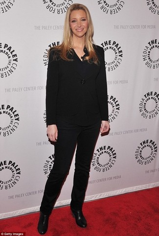 Lisa Kudrow trägt schwarzes Sakko, schwarze Langarmbluse, schwarze enge Hose, schwarze Leder Stiefeletten