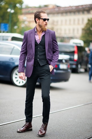 Justin O'Shea trägt violettes Sakko, schwarze Weste, weißes und lila vertikal gestreiftes Langarmhemd, schwarze Anzughose