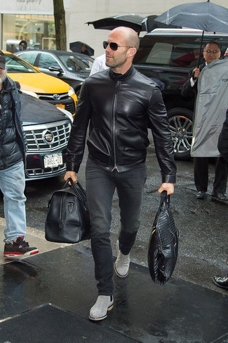 Jason Statham trägt schwarze Leder Bomberjacke, schwarze Jeans, graue Chelsea-Stiefel aus Wildleder