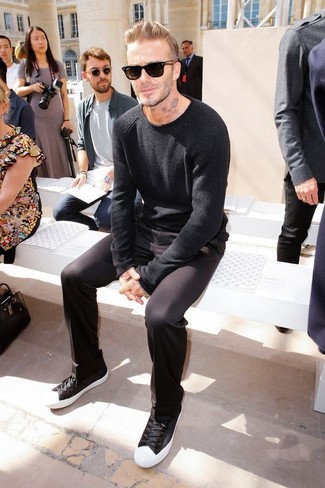 David Beckham trägt schwarzer Pullover mit einem Rundhalsausschnitt, schwarze Chinohose, schwarze und weiße niedrige Sneakers