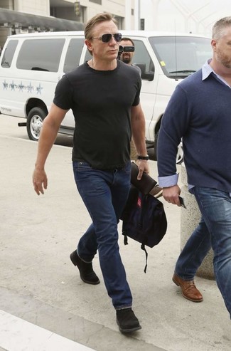 Daniel Craig trägt schwarzes T-Shirt mit einem Rundhalsausschnitt, dunkelblaue Jeans, schwarze Chukka-Stiefel aus Wildleder