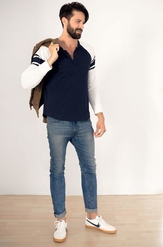 braune Shirtjacke aus Wildleder, dunkelblaues Langarmshirt mit einer Knopfleiste, blaue Jeans, weiße und dunkelblaue Leder niedrige Sneakers für Herren