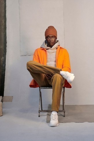 Casual Outfits Herren 2024: Kombinieren Sie eine orange Shirtjacke aus Nylon mit beige Jeans für ein bequemes Outfit, das außerdem gut zusammen passt. Weiße Leder niedrige Sneakers liefern einen wunderschönen Kontrast zu dem Rest des Looks.