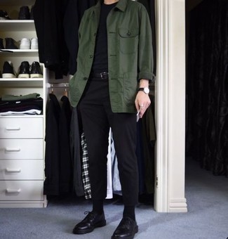 dunkelgrüne Shirtjacke, schwarzes T-Shirt mit einem Rundhalsausschnitt, schwarze Chinohose, schwarze klobige Leder Derby Schuhe für Herren
