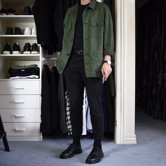 dunkelgrüne Shirtjacke, schwarzes T-Shirt mit einem Rundhalsausschnitt, schwarze Chinohose, schwarze Leder Derby Schuhe für Herren