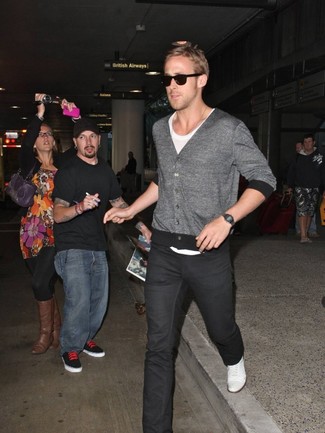 Ryan Gosling trägt graue Strickjacke, weißes T-Shirt mit einem Rundhalsausschnitt, schwarze Jeans, weiße Leinenschuhe