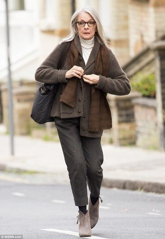 Diane Keaton trägt dunkelbraune Strickjacke mit einem Schalkragen, weißer Rollkragenpullover, dunkelbraune Wollanzughose, braune Wildleder Stiefeletten
