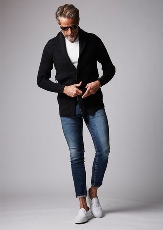 schwarze Strick Strickjacke mit einem Schalkragen, weißes T-Shirt mit einem V-Ausschnitt, dunkelblaue enge Jeans, weiße Slip-On Sneakers aus Segeltuch für Herren