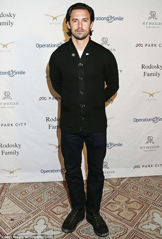 Milo Ventimiglia trägt schwarze Strickjacke, weißes T-Shirt mit einem Rundhalsausschnitt, dunkelblaue Jeans, schwarze Wildlederfreizeitstiefel